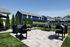 Inviting outdoor barbecue area with multiple grills, surrounded by lush greenery and modern homes, perfect for social gatherings.