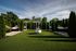 Serene outdoor space featuring lush green lawn, elegant hammocks, and tall trees providing a private oasis.