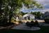 Charming suburban neighborhood view showcasing a modern white house amidst lush greenery, with a tranquil patio area perfect for relaxation.