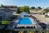 Inviting apartment complex with a pristine outdoor pool, surrounded by cozy seating and sun-drenched lounge areas, perfect for relaxation.