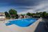 Inviting outdoor swimming pool with modern lounge chairs and shaded seating, surrounded by lush greenery and charming residential cottages.