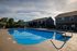 Charming resort-style swimming pool surrounded by modern lounge chairs and lush greenery, perfect for relaxation and enjoyment.