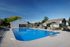 Inviting outdoor swimming pool with sun loungers, set in a serene residential setting under a bright blue sky.