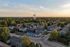 Picturesque aerial view of a serene residential community at sunset, featuring charming townhouses, lush greenery, and a sparkling pool.