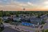 Charming residential community with well-maintained houses, lush greenery, and a sparkling pool under a stunning sunset sky.
