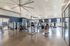Modern fitness center with state-of-the-art exercise equipment, spacious layout, and high ceilings with large ceiling fans.