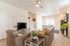Contemporary living space featuring cozy brown leather seating, a sleek TV setup, and an open kitchen with modern fixtures, perfect for relaxing and entertaining.