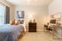 Cozy bedroom with modern decor, comfortable bed, and stylish workspace, featuring natural light and contemporary artwork.