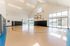 Spacious indoor basketball court with natural lighting and modern glass doors, perfect for recreational activities.