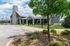 Charming residential building with a modern stone facade, lush landscaping, and welcoming entrance under a bright blue sky.