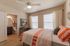 Cozy bedroom with vibrant orange-striped bedding, ample natural light, and an adjoining modern bathroom.