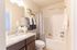 Elegant bathroom featuring a granite countertop, stylish dark cabinetry, and lush hanging plants for a serene atmosphere.