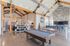Modern community clubhouse showcasing a chic lounge area, pool table, stylish decor, and a high cathedral ceiling with exposed beams.