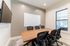 Modern conference room featuring a sleek wooden table, ergonomic chairs, and a large window for natural light.