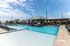 Inviting outdoor pool area with shaded pavilion and comfortable lounge chairs under a clear blue sky.