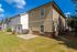 Charming two-story apartment exterior with beautiful siding, spacious backyard, and lush green lawn under a vibrant blue sky.