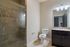 Elegant bathroom with a spacious glass shower, sleek granite countertop, and modern lighting, ensuring a luxurious feel.