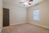 Bright and airy bedroom with plush carpet, elegant ceiling fan, and natural light streaming through the window.