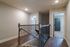 Chic modern interior with wood flooring and stylish railing leading to cozy carpeted bedrooms, offering a welcoming ambiance.