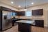 Modern kitchen with elegant dark cabinets, granite countertops, and high-end stainless steel appliances under contemporary lighting.