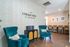 Inviting apartment common area featuring stylish teal armchairs, chic wallpaper, and a modern bar seating arrangement at The Collective at Kennesaw.