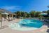 Inviting swimming pool area with sun loungers and umbrellas, surrounded by lush greenery for a perfect relaxation retreat.