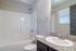 Modern bathroom featuring a sleek granite countertop, elegant sink, and a spacious tub with a polished chrome showerhead.