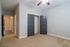 Bright bedroom with plush carpet, modern ceiling fan, and inviting hallway. Elegant double doors open to a spacious closet.