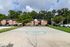 Charming apartment complex with brick facades, nestled among lush greenery, featuring a vibrant outdoor basketball court.