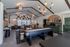Chic recreational lounge with stylish lighting, cozy seating, wall art, and a shuffleboard table, perfect for entertaining.