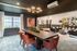 Elegantly designed dining area with plush orange chairs, modern chandelier, and stylish open living space, perfect for entertaining.
