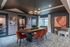 Chic and modern dining area with elegant lighting, vibrant orange chairs, and artistic wall decor, creating a warm and inviting atmosphere.