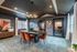 Elegant conference room with a sophisticated table, vibrant orange chairs, chic artwork, and modern lighting.
