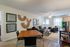 Modern living and dining area with stylish decor, including woven wall art, black leather seating, and a wooden dining table, all accented by natural light and a cozy atmosphere.