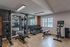 Contemporary home gym featuring state-of-the-art exercise equipment, including weight racks, a mirror wall, and a stationary bike, with natural light streaming through large windows.