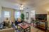 Cozy living room with elegant decor, featuring a sleek black sofa, modern coffee table, and large TV. Warm lighting and decorative plants add charm to the inviting space.
