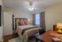 Cozy bedroom with elegant decor, featuring a comfortable bed, stylish pillows, and a well-lit desk area, perfect for relaxation.