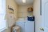Bright laundry room with modern washer and dryer, elegant shelving, and stylish storage solutions.
