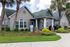 Charming leasing center with a cozy porch, framed by palm trees and vibrant flower beds, offering a warm welcome.