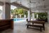 Inviting outdoor space with a covered patio, picnic tables, and a sparkling swimming pool surrounded by lush palm trees.