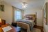 Cozy bedroom with elegant decor, featuring a plush bed adorned with colorful pillows, stylish artwork, and a functional study desk.