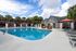 Inviting outdoor pool area with wicker cabanas and sun loungers under palm trees, perfect for relaxation and leisure.