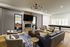 Modern living room with chic decor, featuring a comfortable seating area, stylish chandelier, and large window offering natural light.