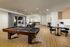Spacious modern living area featuring a stylish pool table, cozy seating, and elegant kitchenette, perfect for entertainment and relaxation.