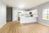 Spacious modern kitchen with sleek white cabinetry, stainless steel appliances, and elegant wood flooring, perfect for culinary adventures.