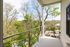 Charming balcony view overlooking lush trees and a serene landscape, perfect for relaxation.