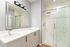 Elegant bathroom with dual sinks, modern mirror, and a glass-enclosed marble shower.