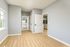 Bright and airy apartment interior featuring elegant hardwood floors, pristine white doors, and a view into a modern kitchen.