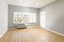 Bright and inviting room with elegant wooden flooring, large windows allowing natural light, and soothing gray walls.