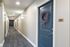 Inviting apartment hallway with modern lighting, plush carpet, and a charming navy door adorned with a lavender wreath.
